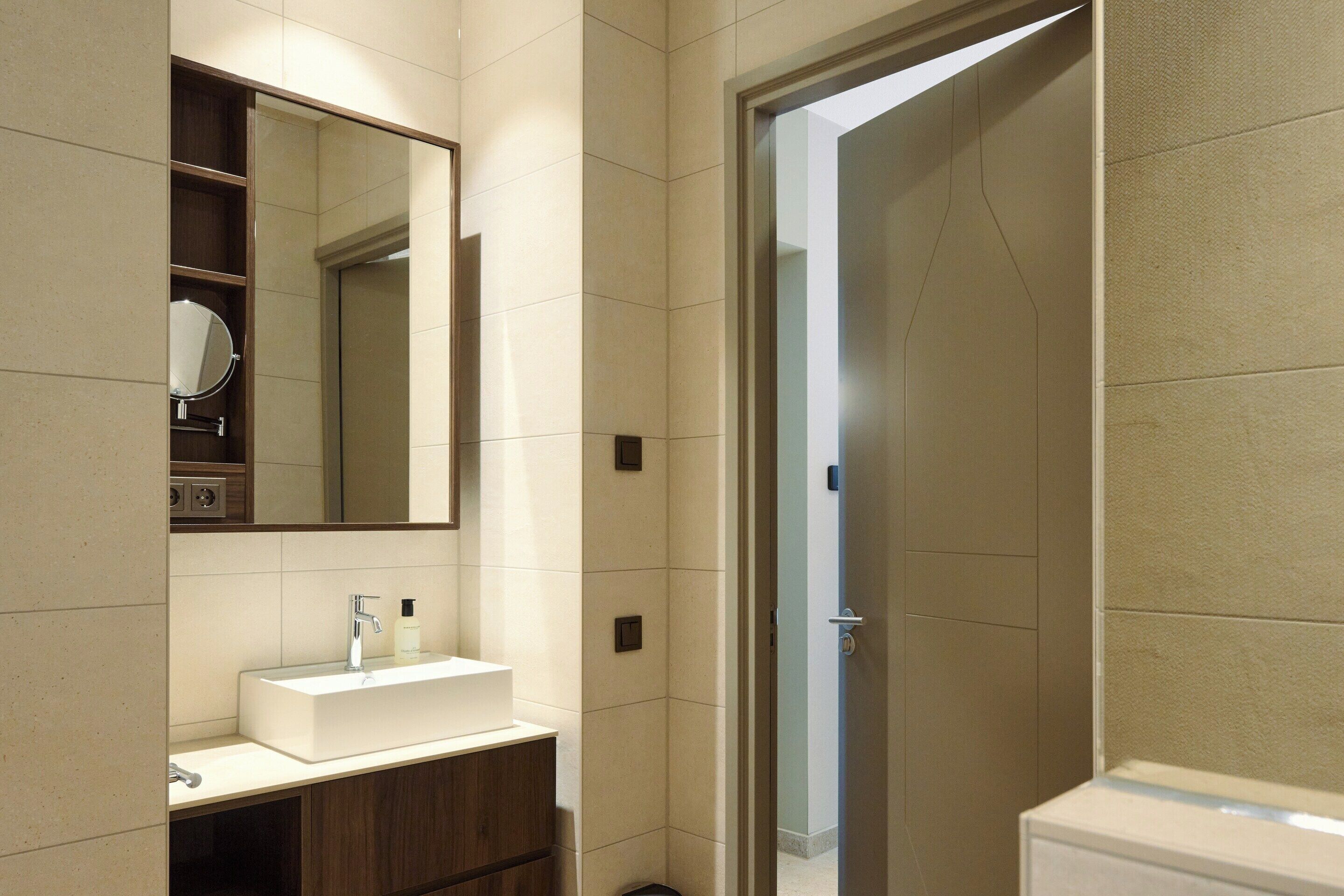 A bathroom with a white sink, a mirror, and a shower area.