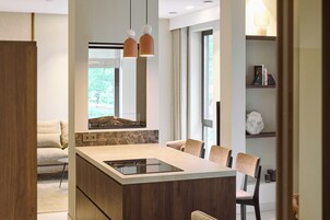 Una cocina moderna con una isla central, luces colgantes y vistas al exterior.