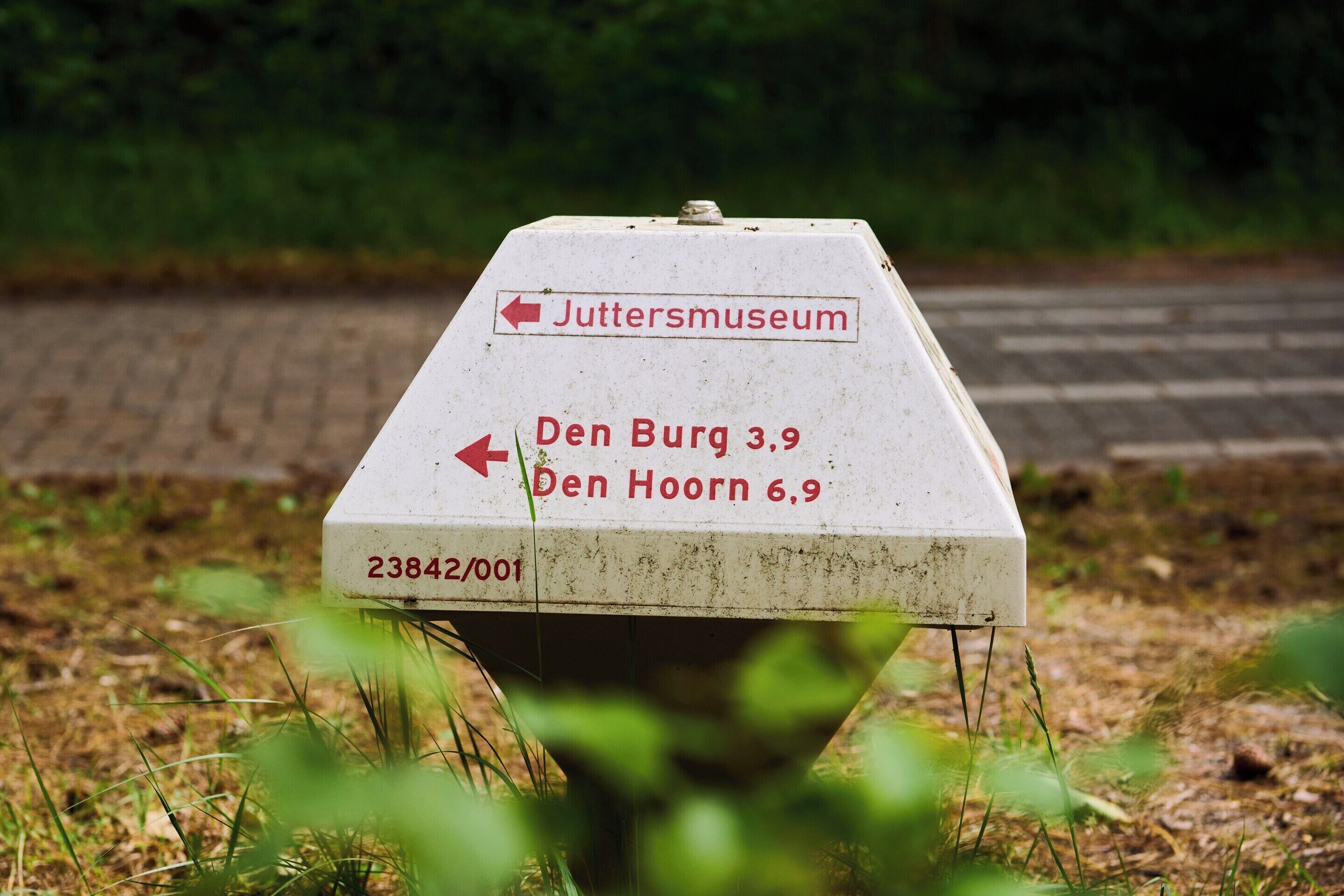 A directional sign with arrows pointing to 'Juttersmuseum,' 'Den Burg 3.9,' and 'Den Hoorn 6.9.'