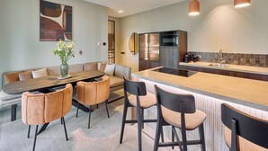 Una cocina moderna con una isla central, taburetes de bar, una mesa de comedor con sillas y un espejo grande.