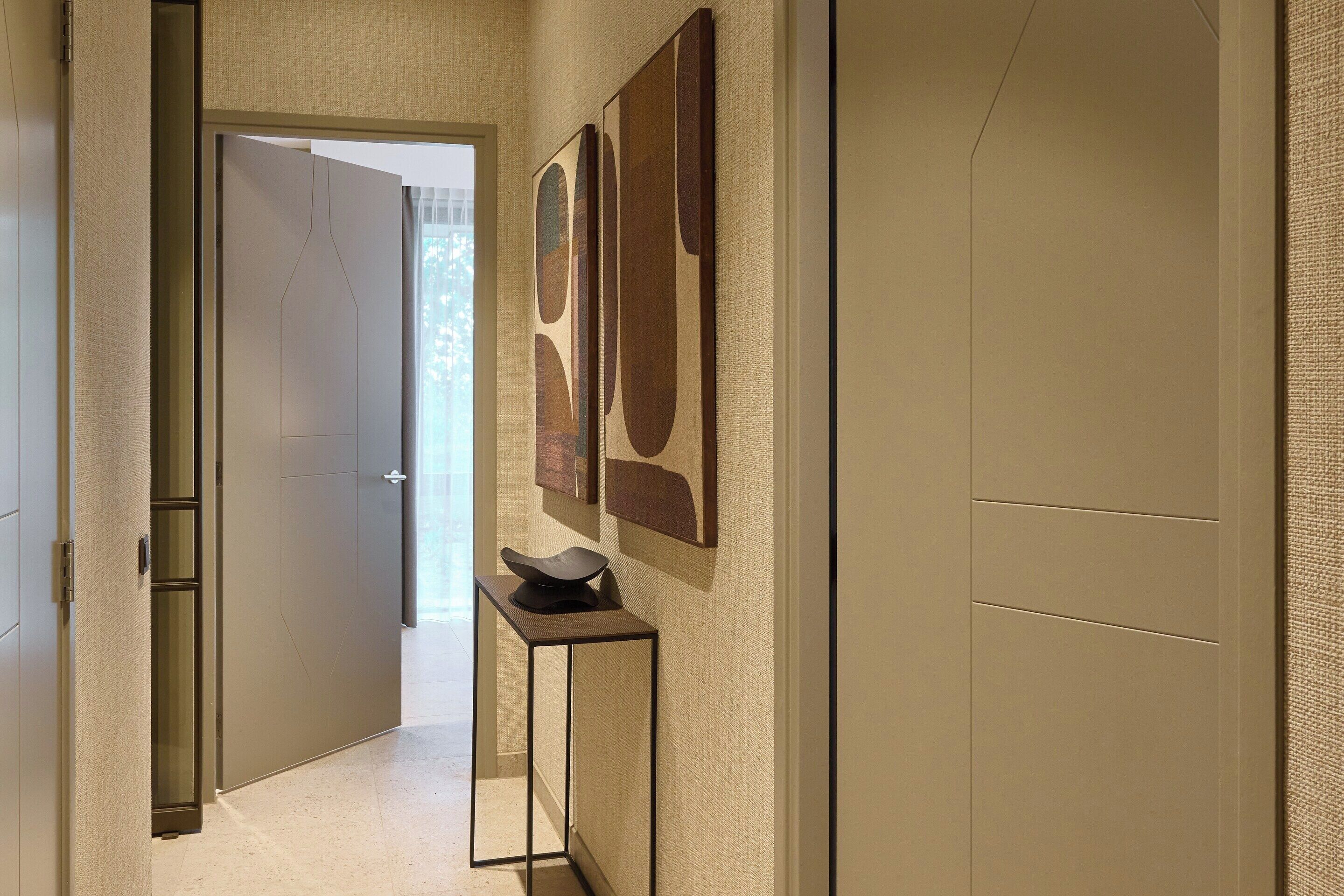A hallway with a door, a small table, and abstract wall art.