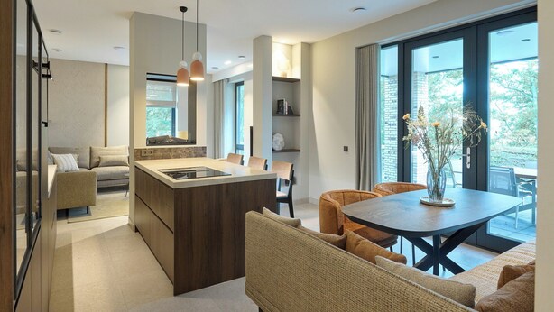 Una cocina moderna con una isla central, comedor con sillas y amplios ventanales con vistas.