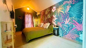 Un dormitorio con cama, mesita de noche, aire acondicionado instalado en la pared, ventana con cortinas y un llamativo mural floral.