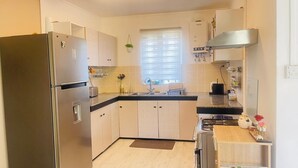 Una cocina moderna con un refrigerador de acero inoxidable, una estufa a gas y una encimera de madera.