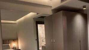 A modern bedroom with a glass-top desk, grey wardrobe, and a mirror reflecting the room. - The Pilgrim Ephesus Hotel (Selcuk)