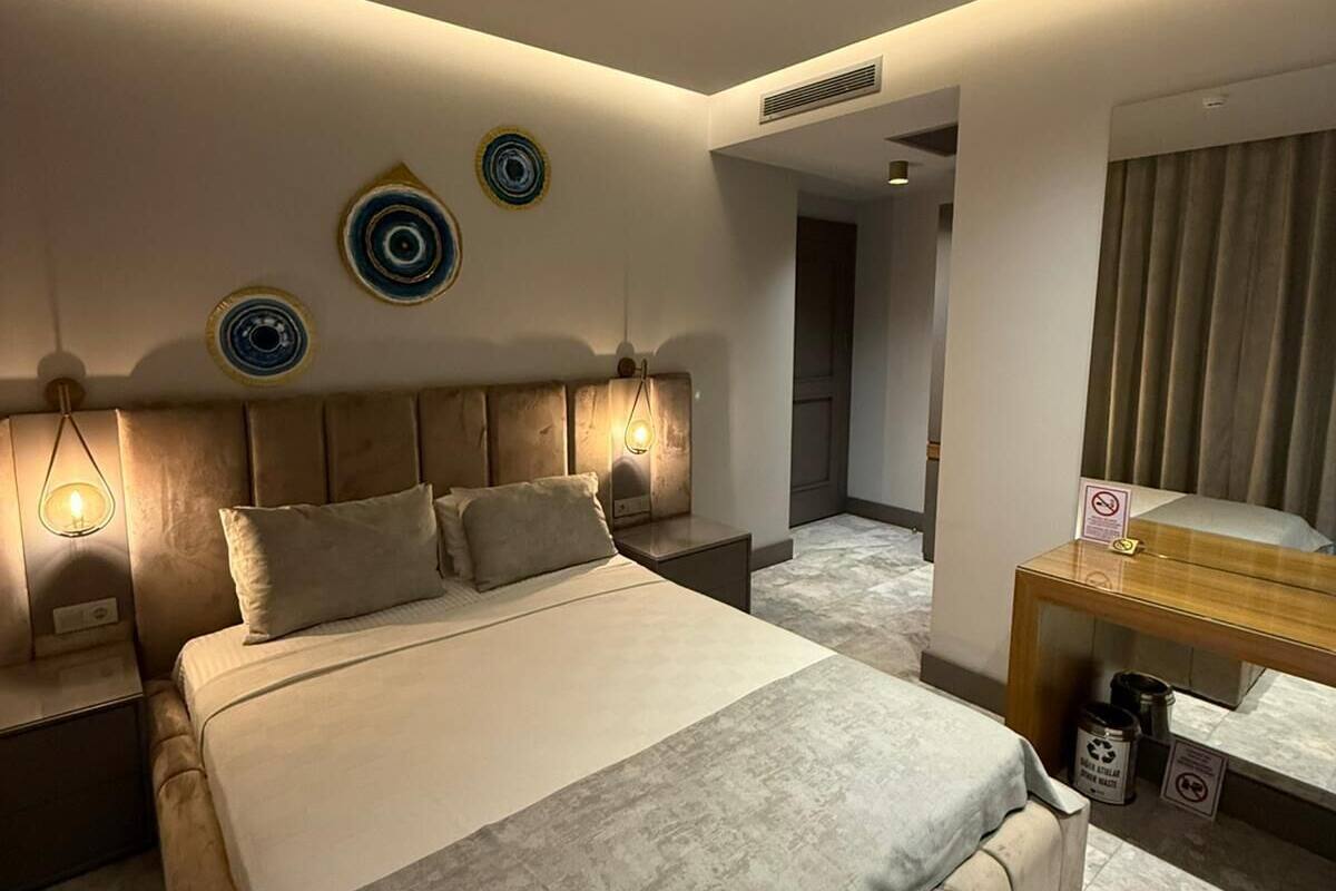 A modern hotel room with a large bed, bedside tables, a mirror, and decorative wall plates.