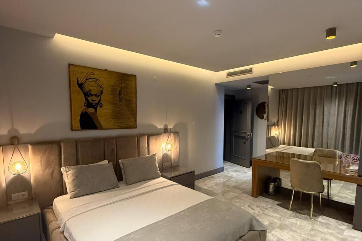 A modern bedroom with a large bed, bedside tables, a desk, and a chair.