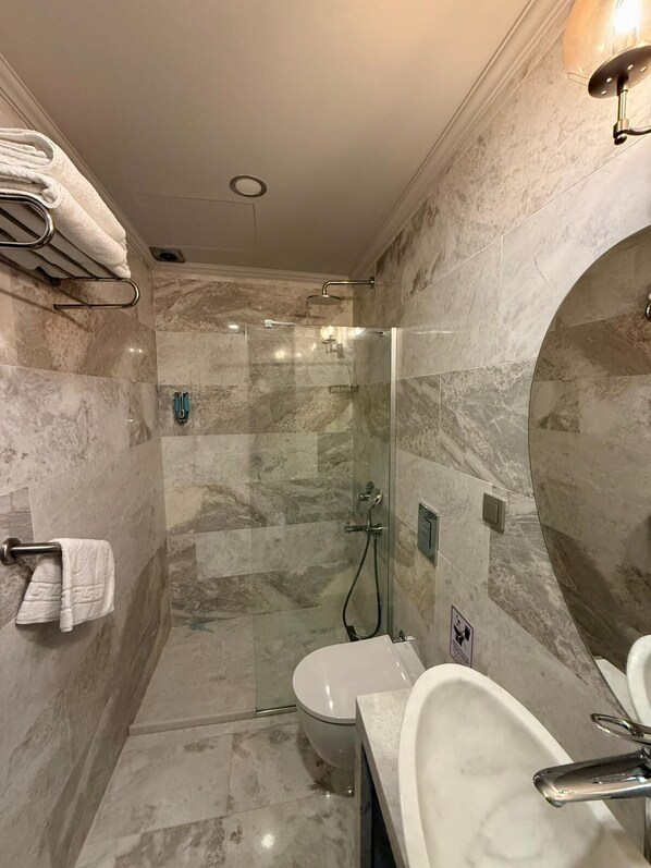 A modern bathroom with a glass-enclosed shower, a toilet, and a sink with a mirror. - The Pilgrim Ephesus Hotel (Selcuk)