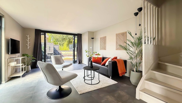 Ein modernes Wohnzimmer mit einer Couch, einem Sessel und einem Fernseher.