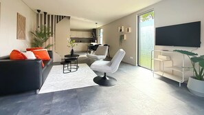 A modern living room with a sofa, armchair, coffee table, and a TV. - Modern Forest Home Near Beach (Bergen)