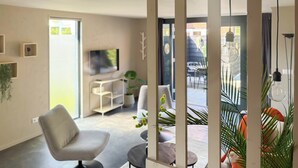 Ein modernes Wohnzimmer mit Sofa, Fernseher und Blick ins Freie.