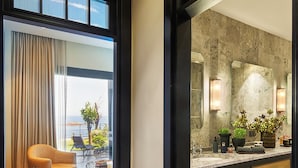 Um banheiro moderno com um espelho grande, bancada de mármore e vista para o exterior.