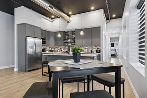 A modern kitchen with a central island, stainless steel appliances, and pendant lighting. - The Lofts - Unit 2 (Fennville)