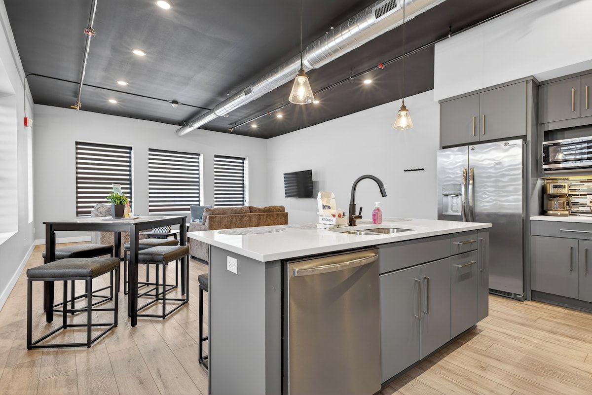 A modern kitchen with a central island, stainless steel appliances, and a dining area with bar stools.