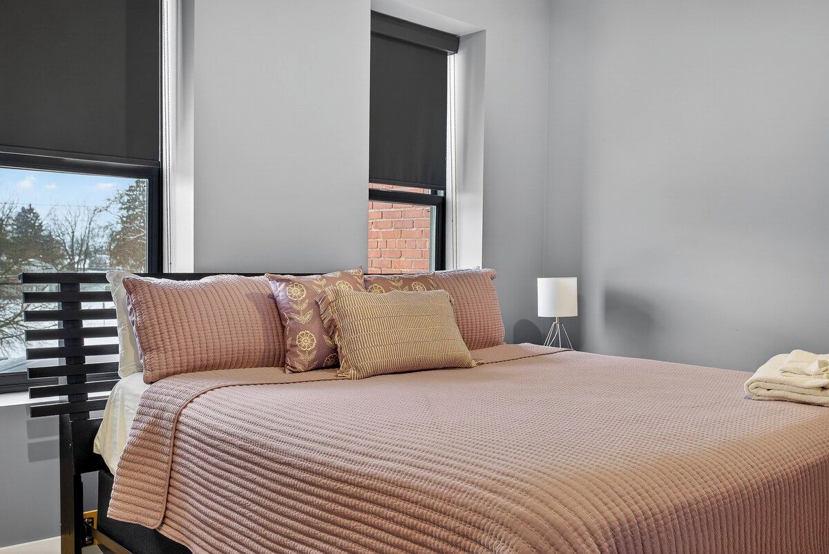 A bedroom with a bed, pillows, a window, and a nightstand.