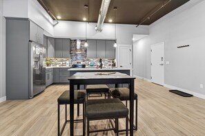 Una cucina moderna con isola centrale, sgabelli da bar ed elettrodomestici in acciaio inossidabile.
