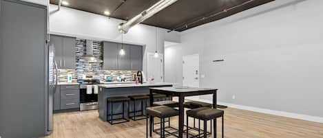 Una cocina moderna con una isla central, taburetes de bar y una mesa de comedor.