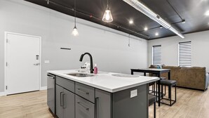 Et moderne køkken med en central ø, et spiseområde med bord og stole, samt en sofa.