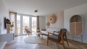 A modern living room with a sofa, two chairs, a coffee table, and a large window. - Stylish Coastal Home With Garden (Sint Maarten)