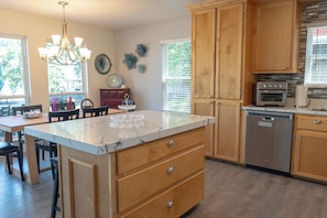 A kitchen with wooden cabinets, a marble countertop, a dishwasher, and a built-in oven. - Spacious 5-bedroom, 4-bath lakefront home with modern comforts, scenic views, and plenty of room for family and friends—perfect for a relaxing getaway or fun-filled retreat. (Mabank)