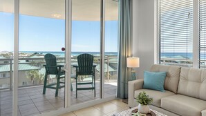 A balcony with a view of the ocean, a green chair, a beige sofa, and a lamp. - Destin West Studio Villa 501 ~ Amazing Ocean Views ~ Free Beach Service (Fort Walton Beach)