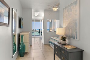 Een hotelkamer met een bed, een kaptafel, kunstwerken en uitzicht op de oceaan.