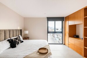 Ein Schlafzimmer mit Bett, Nachttisch, Lampe, Fenster und einem Holzschrank.