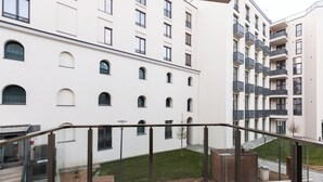 A modern building with multiple balconies, a courtyard with a lawn, and a staircase leading to an entrance. - Nest Inn Jasmine Apartment (Oradea)