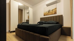 A modern bedroom with a large bed, a mirror, a painting, and an air conditioning unit. - Nest Inn Jasmine Apartment (Oradea)