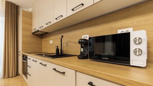 A modern kitchen with a microwave, coffee maker, and wooden cabinets. - Nest Inn Jasmine Apartment (Oradea)