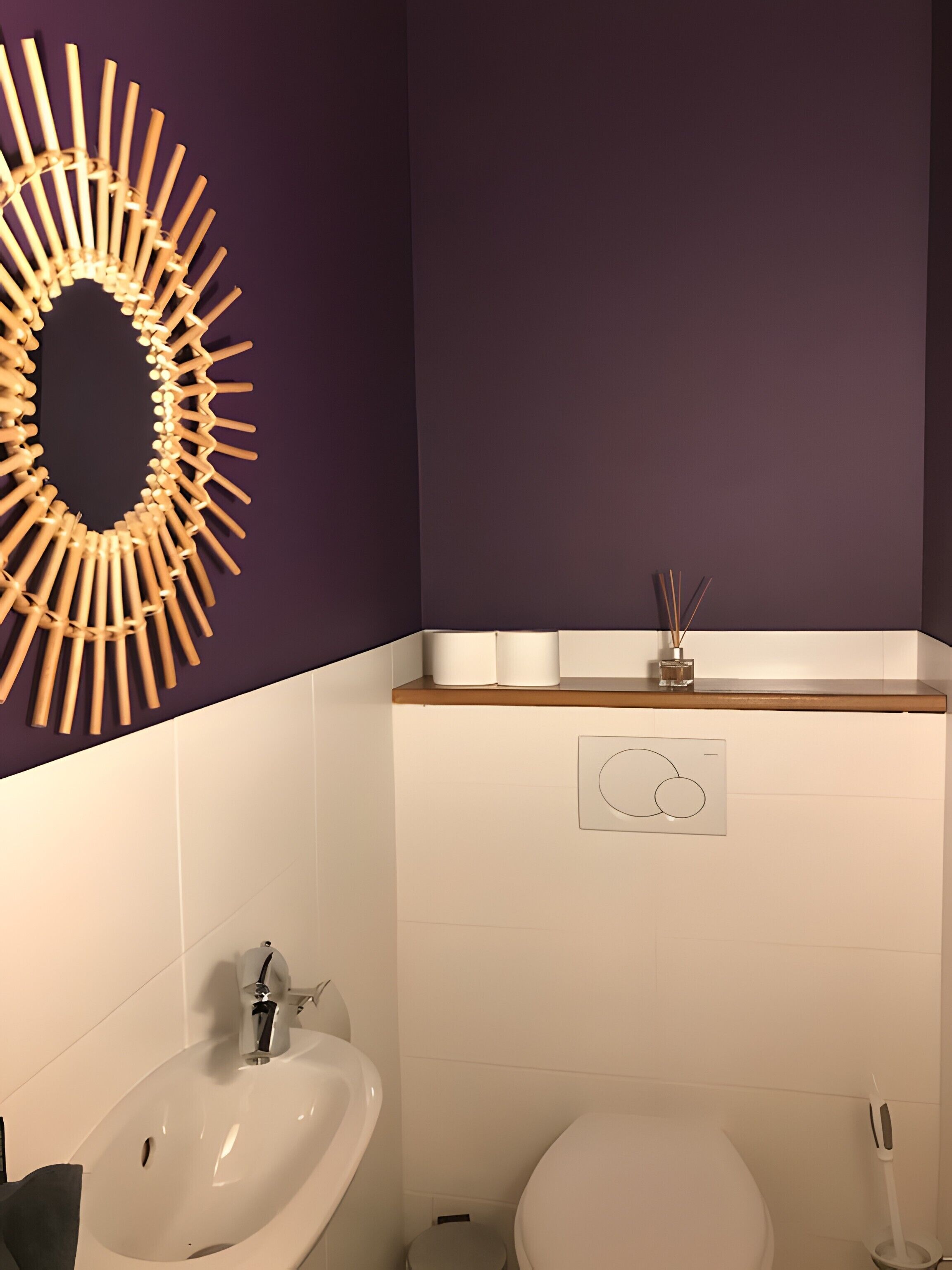 Ein Badezimmer mit weißem Waschbecken, Toilette und einem Spiegel an der Wand.