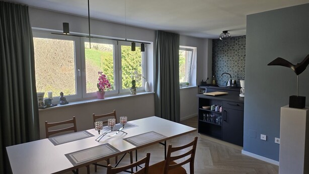 A modern kitchen with a dining area, large windows, and a view of greenery. - Beautiful 2-room apartment in the heart of Taucha (Taucha)