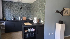 A modern kitchen with patterned backsplash, black cabinets, and a wooden countertop. - Beautiful 2-room apartment in the heart of Taucha (Taucha)
