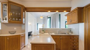 Una cocina moderna con armarios de madera, encimera blanca y una estantería empotrada para vinos.