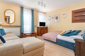 Une pièce comprenant un lit, deux canapés, un téléviseur, une armoire en bois et un miroir.