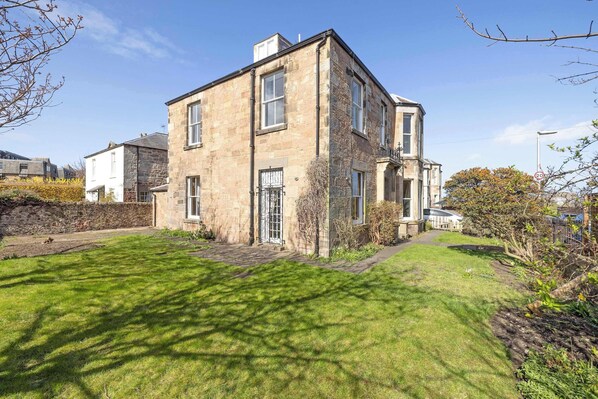 A stone building with a well-maintained lawn and a clear sky.