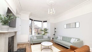 A living room with a fireplace, two sofas, a coffee table, and a chandelier. - Detached House with Sea Views & Parking (North Berwick)