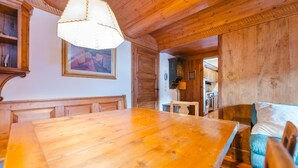 Una mesa de comedor de madera con sillas, una lámpara colgante, un cuadro en la pared y un mueble de madera.