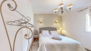 Une chambre à coucher avec un lit, des lampes de chevet, une chaise et un luminaire fixé au mur.