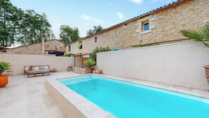 Une piscine avec un mur en pierre et un banc.
