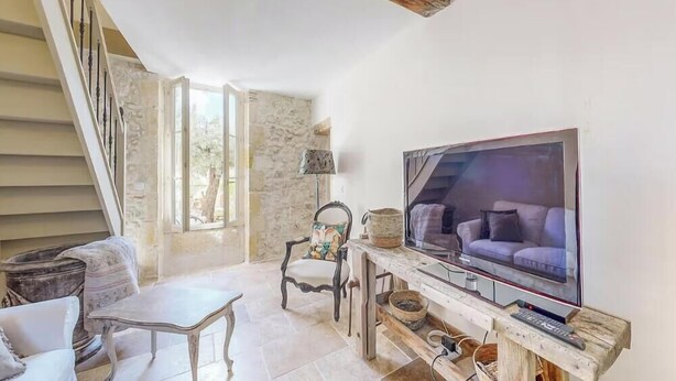 Un salon avec un téléviseur, un canapé, un fauteuil et un escalier.