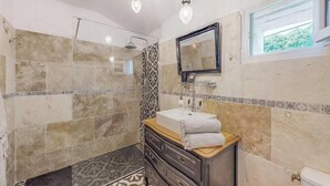 Une salle de bain avec une douche, un lavabo avec un miroir et des carreaux décorés.