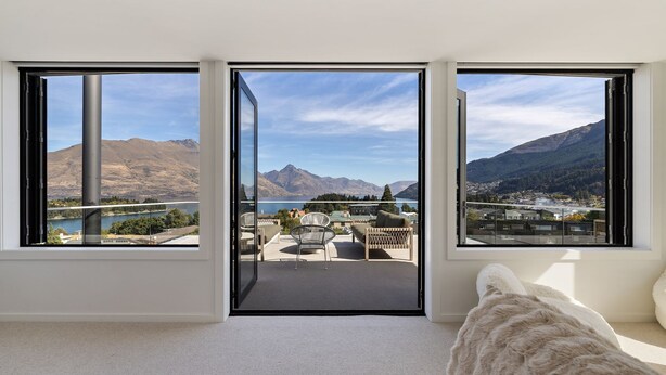 A room with three large windows offering a mountain view, a sofa, and a dog. - Queenstown Hill House Only -  A seamless sense of luxury for families or groups of friends. (Queenstown)