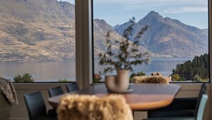 A dining area with a view of mountains and a lake. - Queenstown Hill House Only -  A seamless sense of luxury for families or groups of friends. (Queenstown)
