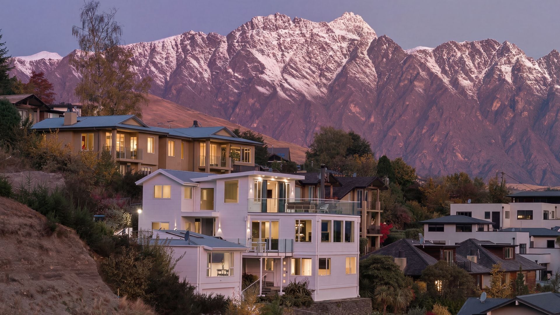 A residential area with modern houses, a mountain backdrop, and a clear sky.