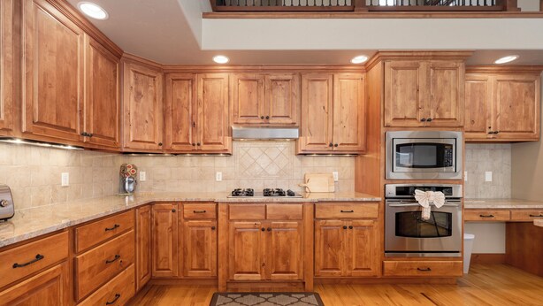 A kitchen with wooden cabinets, a microwave, an oven, and a gas stove.
