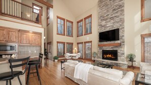 A spacious living area with a fireplace, wooden flooring, and a high ceiling. - 892 Saddle Ridge Ultra luxurious 4 bedroom home, views, 2 living spaces and more (Granby)