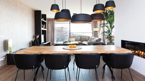 A modern dining area with a wooden table, black chairs, and pendant lights. - Chic Apartment for 8 With Seaview (Egmond aan Zee)