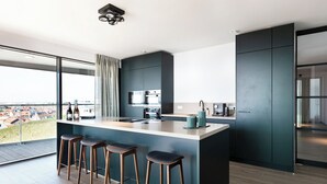 A modern kitchen with a large island, bar stools, and a view of the city. - Chic Apartment for 8 With Seaview (Egmond aan Zee)