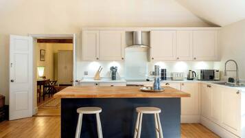 A modern kitchen with a central island, white cabinetry, and a dining area visible in the background.